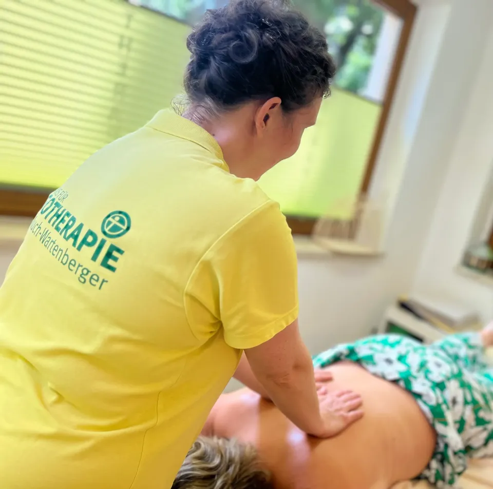 Ergotherapeutin der Praxis im gelben Poloshirt behandelt eine Patientin